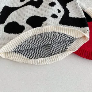 Detailed view of baby knit romper, black and white cow print pattern, soft infant knitwear.