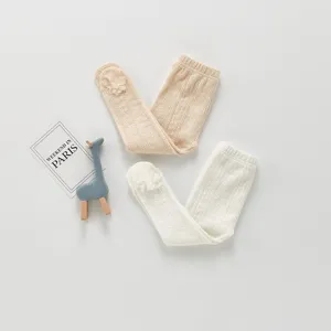 Vue détaillée de collants côtelés pour bébés avec fleurs 3D à la cheville beige et blanc.