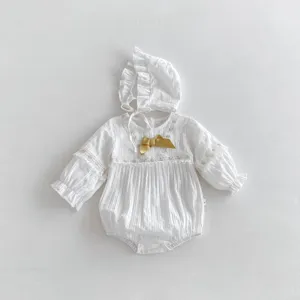 Vue détaillée du body bébé fille blanc en coton avec bordure en dentelle et nœud doré.