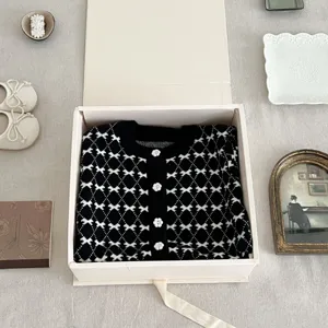 Classic black and white knit cardigan for baby girls with cute flower buttons chic.