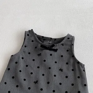 Detailed view of infant dark grey sleeveless vest dress with black polka dots and cute bow accent.