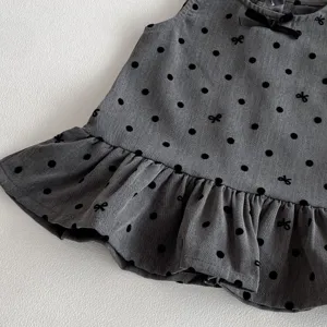 Close-up detail of baby girl grey dress with black polka dots and cute bow ruffle hem.