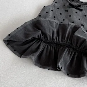 Detailed close-up view of autumn baby girl polka dot vest dress with cute bows and ruffles.