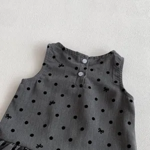 Baby girls grey polka dot vest dress detail, featuring cute black bow print and back buttons.