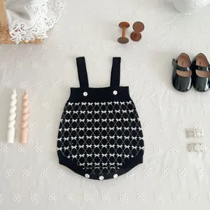 Black and white knit baby romper with flower buttons flat lay detail shot for infant daily wear.