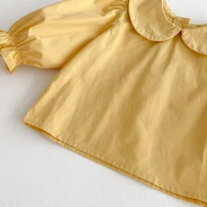 Close-up detail of yellow baby girl cotton blouse with cute peter pan collar and puff sleeves.
