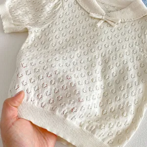 Close-up view of baby hollow-out knit top detail, featuring soft fabric and cute bow collar.