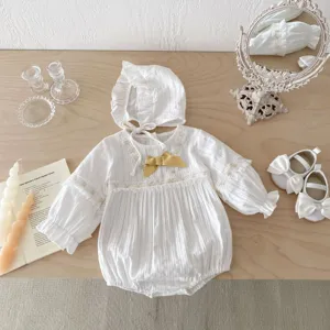 Vue détaillée d'un adorable body en dentelle pour bébé avec capuche et nœud doré.