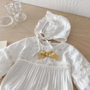 Vue détaillée de la combinaison en dentelle blanche pour bébé avec bonnet et nœud, doux.
