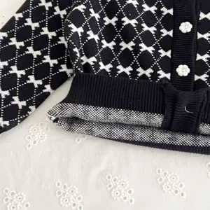 Black and white baby knit cardigan detail close up, cute floral buttons infant sweater