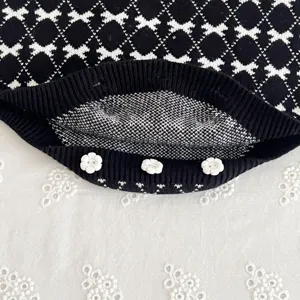 Black and white knit cardigan detail for baby girls, featuring cute floral buttons and chic pattern.