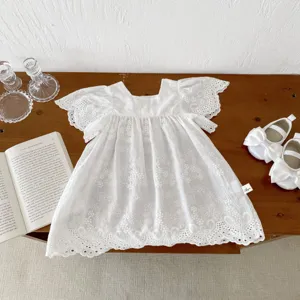 Detail shot of white cotton lace baby girl dress with delicate embroidery and flutter sleeves.