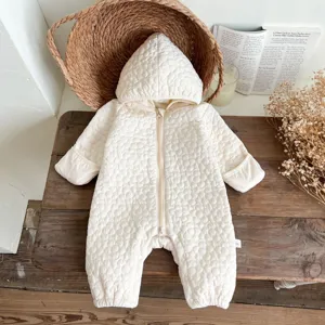 Detalle de mameluco acolchado de invierno para bebé, mono cálido y forrado en crema.