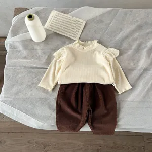 Detailed view of baby ribbed long-sleeve top and corduroy pants set with lace shoulder trim.