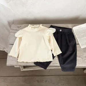 Detailed view of baby ribbed top and corduroy pants set, cozy and retro children's outfit.