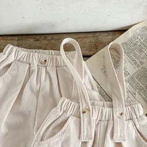 Detail shot of baby corduroy overalls, soft ribbed texture and buttons, vintage retro style.