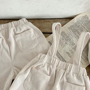 Corduroy baby pants detail shot, soft beige texture, cute pocket and strap design, vintage flat lay.