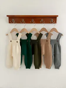 Minimalist knit baby strap pants scene, detailed close-up of textured fabric and wooden buttons.