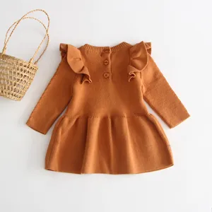 Close-up detail view of the cute caramel knit baby dress shoulder ruffles and back buttons.