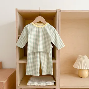Cozy cotton baby checkered pajama set hanging in a neat wooden shelf scene detail view.