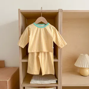 Detailed view of the yellow checkered baby loungewear set hanging nicely on wooden shelf.