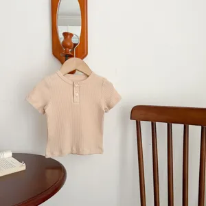 Dettaglio t-shirt neonato a costine manica corta, top henley in cotone morbido, abbigliamento neutro.