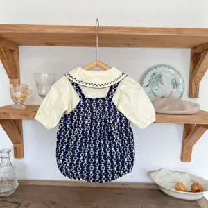 Detailansicht des niedlichen Babyset mit Blumenstickerei auf dekorativem Holzregal im Hintergrund