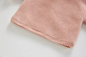 Infant pink knit sweater detailed close-up shot showcasing fine texture and ribbed cuffs.