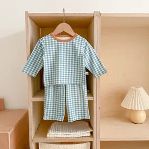 Detailed view of baby blue gingham long sleeve top and pants set hanging in wooden shelf.