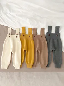 Infant knitted strap pants detail shot showing fine rib texture and cute wooden buttons.