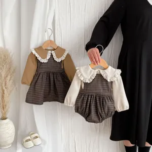 Detailed view of baby girl plaid dress and romper with lace collar, autumn style.