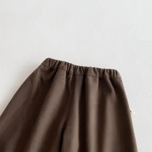 Gros plan sur la taille élastique du pantalon marron pour enfants, joli tissu doux.