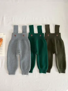 Detailed view of baby knit overalls showing button closures, soft texture, and ribbed cuffs.