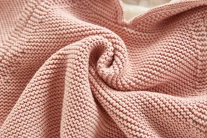 Detailed close-up shot of baby pink knit fabric texture, soft and warm infant cardigan material.