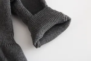 Dark gray knitted infant dress sleeve detail, soft and warm winter baby clothing close-up.