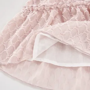 Girls pink textured tiered summer dress close-up showing soft fabric and inner lining details.