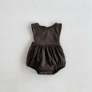 Close-up detail of dark plaid baby romper, soft infant sleeveless clothing with snap closure.