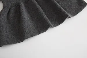 Detailed view of baby girls dark gray knit pleated skirt, soft and warm winter fabric.