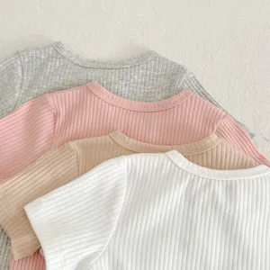 Primo piano dettagliato di morbide magliette in cotone a costine per neonati in colori assortiti.