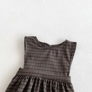 Detailed view of baby girl brown plaid sleeveless dress fabric texture and pleated waist