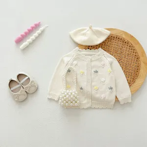 Detailed view of cute baby girl knit cardigan set with floral embroidery and pearl bag details.