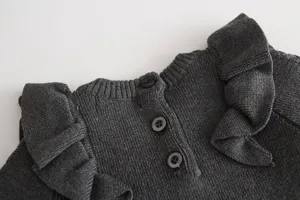 Baby girl knit dress detail, dark grey winter sweater with cute shoulder ruffles and back buttons.