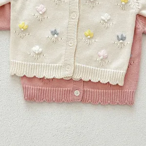 Detailed close-up of handmade embroidered floral knit cardigan for baby girls, soft texture.