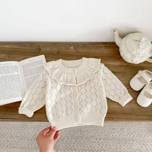 Close-up detail of cream baby knit cardigan with hollow-out pattern and big ruffle collar.