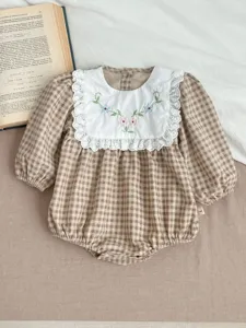 Detailed view of baby girl plaid romper featuring an embroidered lace collar and long sleeves.