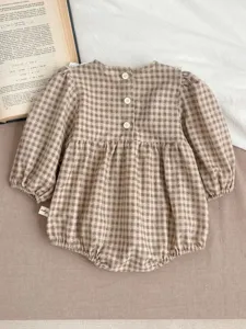 Detailed view of baby girl plaid romper featuring back buttons, long bubble sleeves and cute design.