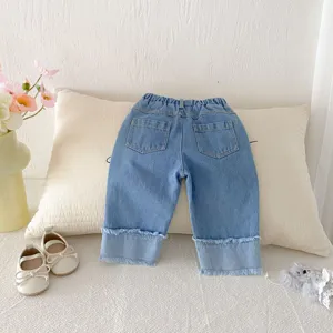 Detailed shot of children washed denim pants featuring wide-leg fit and cute frayed hem.