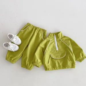 Detalle de chándal verde para niños con chaqueta de media cremallera y bolsillo.
