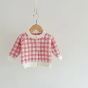 Détail gilet tricot bébé carreaux rose blanc, jolie fermeture boutons texture bord.