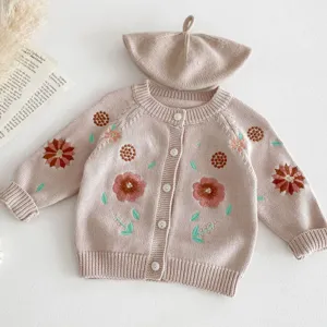 Detailed view of baby knit cardigan and beret set with delicate floral embroidery design.